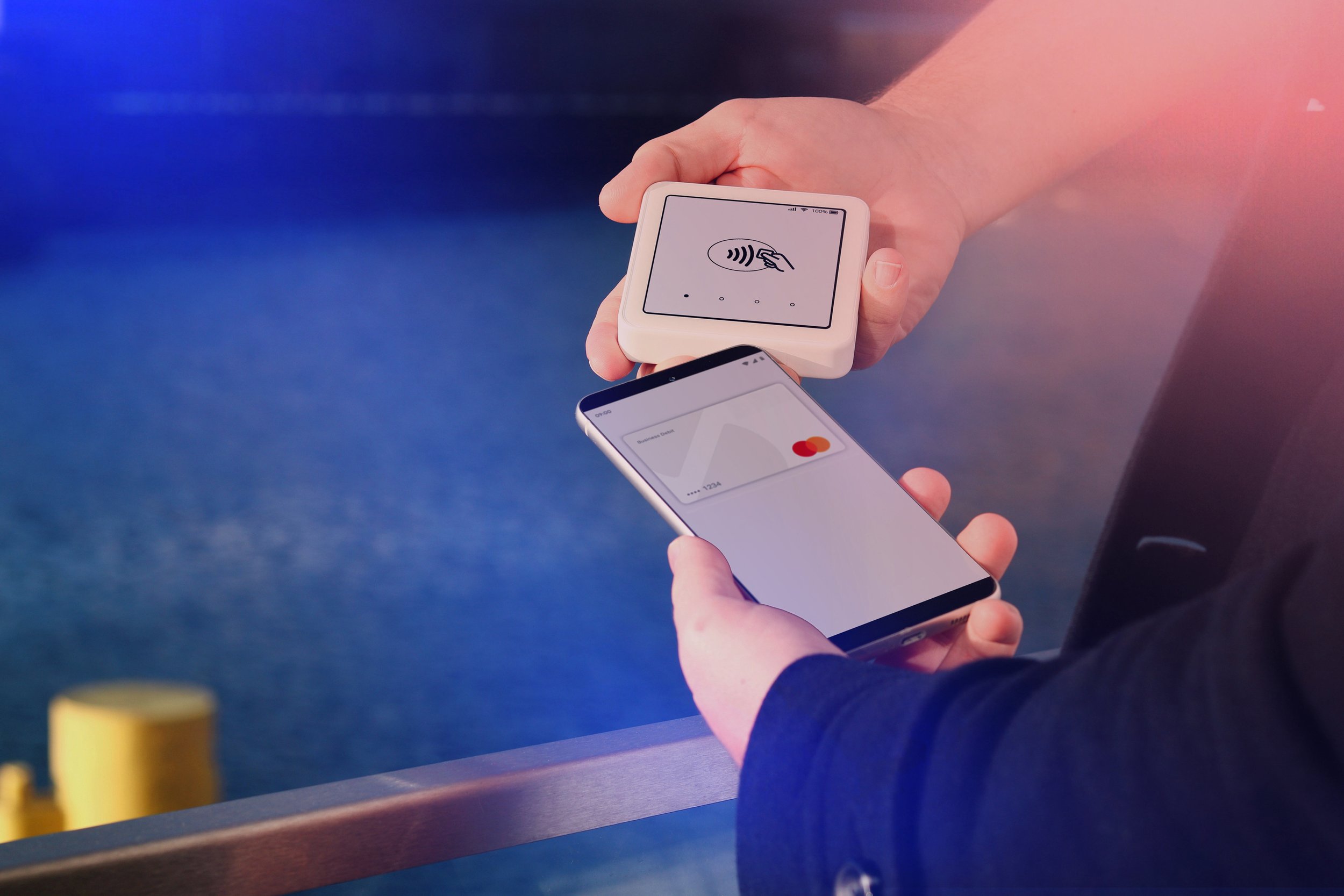 Hands holding phone and haptic card showcasing Mastercard’s audio-haptic branding.