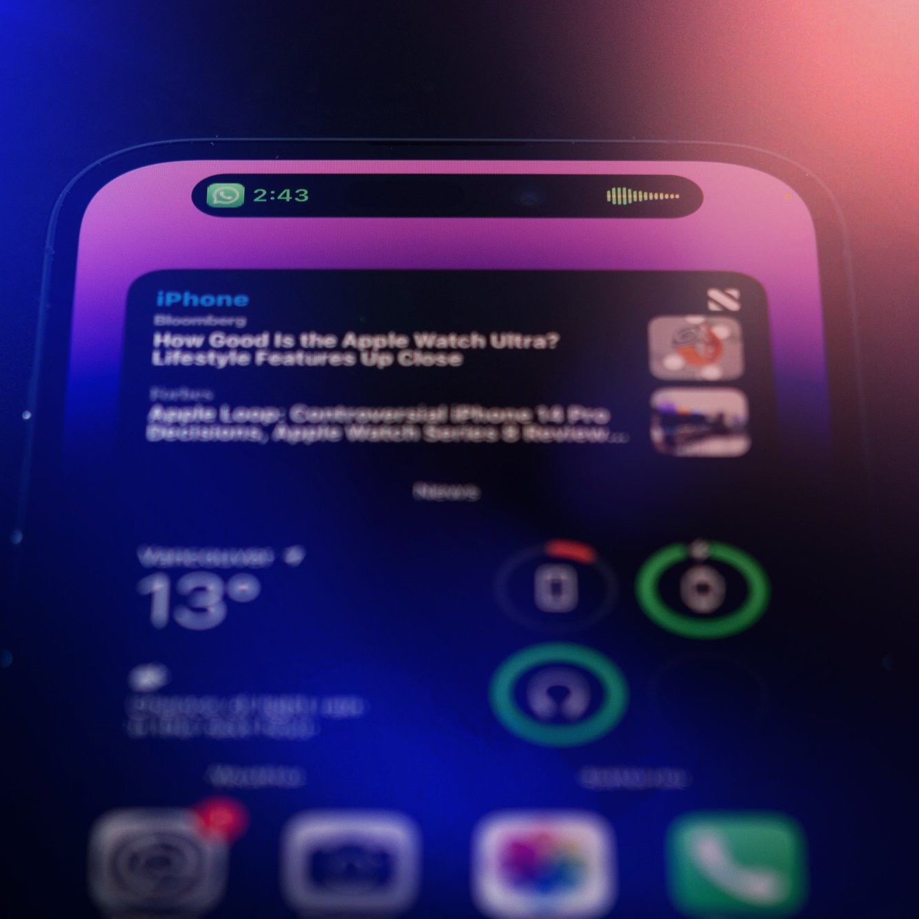 Close-up of an iPhone screen displaying a Bloomberg news article about the Apple Watch Ultra, with weather forecast and app icons visible.