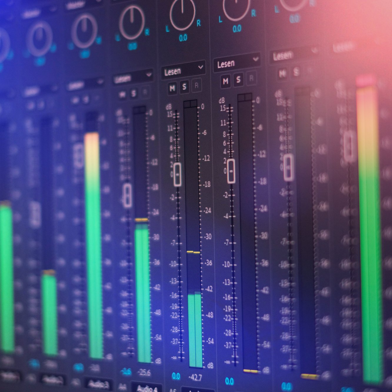 Digital audio mixing console displaying multiple faders, meters, and controls with colorful LED indicators.