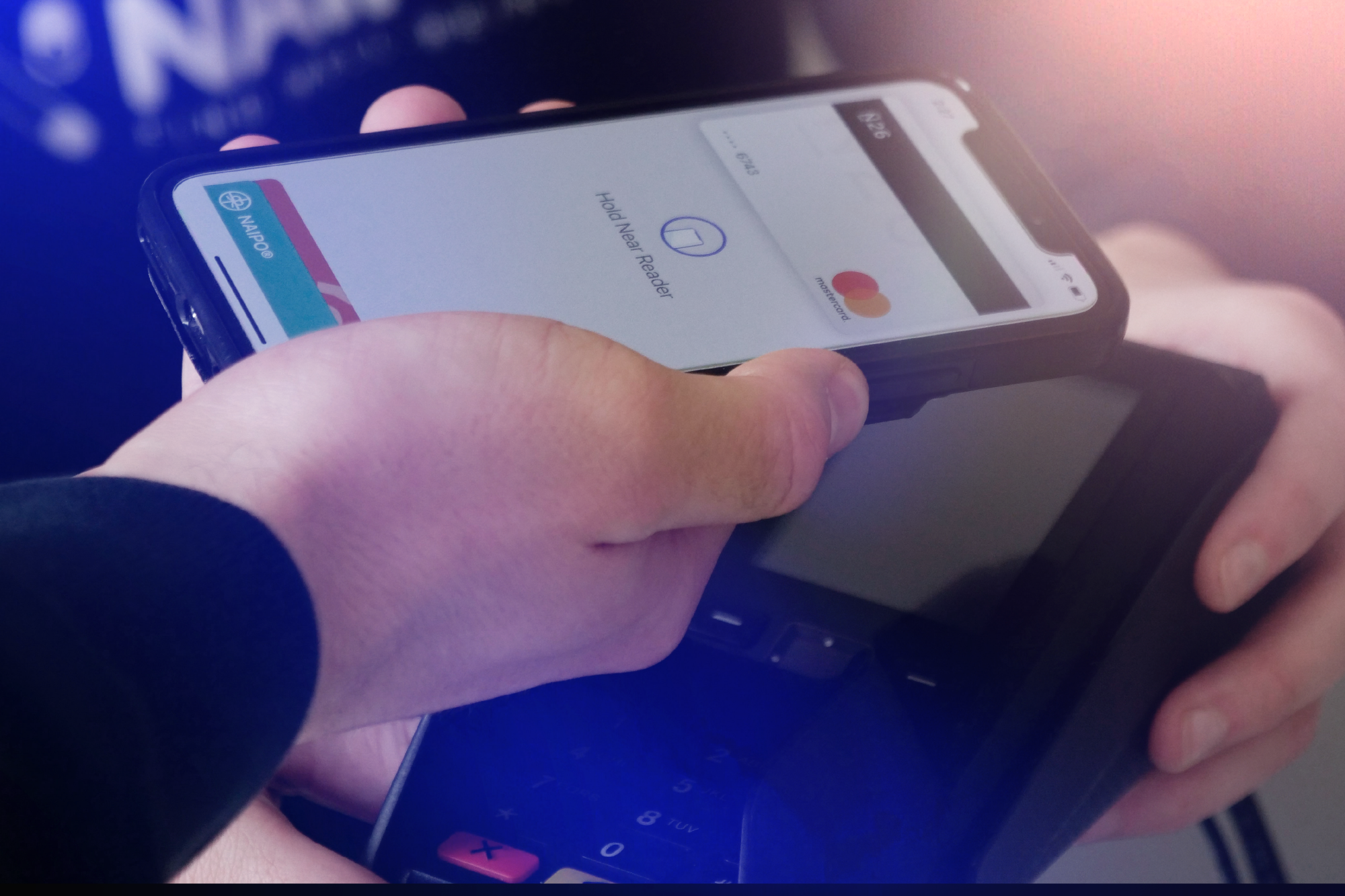 Person holding a smartphone with a screen displaying a payment app, using a contactless card reader device.