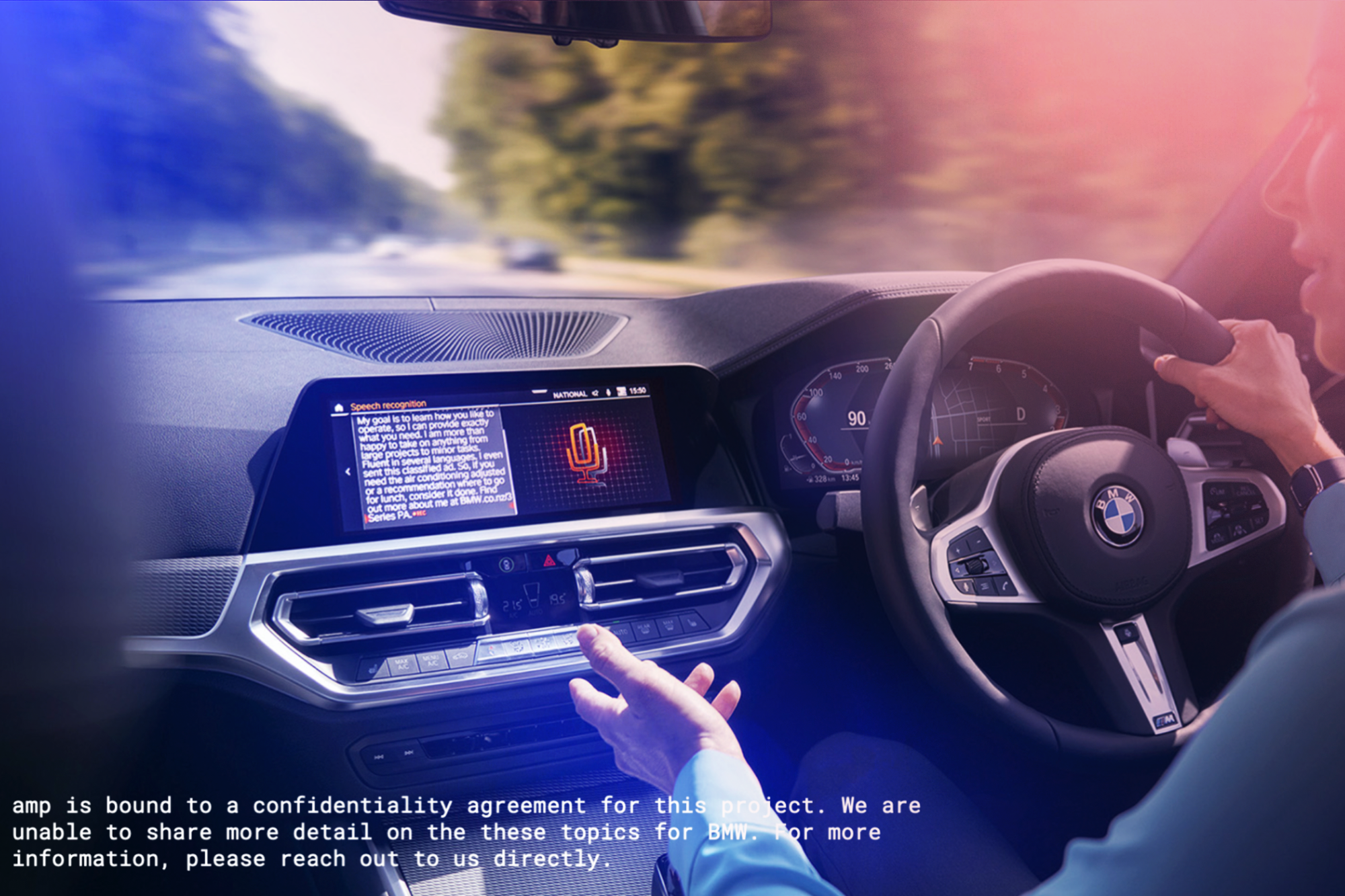 Interior of a BMW vehicle with a person's hands on the steering wheel and dashboard display showing speech recognition and climate controls, with a blurred outdoor view through the windshield.